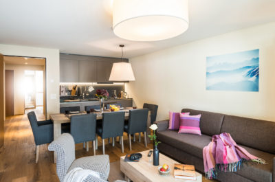 Wohnzimmer mit Esstisch für acht Personen in der Ferienwohnung in Laax im Aparthotel Peaks Place