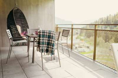 The balcony of an apartment at Peaks Place Hotel Laax with hanging chair and seating area