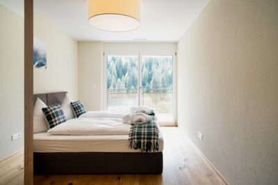 Ein Schlafzimmer in einer Ferienwohnung des Apartment Hotels Peaks Place Laax