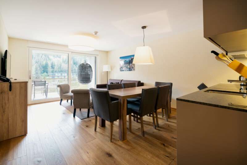 The living area and dining table of a 3.5-room apartment at Peaks Place Hotel Laax